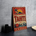 A vintage-style sign for Tahiti, featuring a tropical landscape with palm trees, a sun, and a mountain.