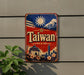 A vintage-style sign with the word "Taiwan" prominently displayed, featuring a sun, mountains, and a temple in the background.