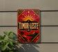 A vintage-style sign with a red background and gold accents, featuring a sun and palm trees, is mounted on a wall.