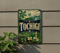 A vintage-style sign with the word "Tochigi" displayed prominently, featuring a sun, mountains, and a bridge.