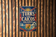 A vintage metal sign with the text "TURKS AND CAICOS ISLANDS" displayed prominently against a wooden background.