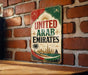 A vintage-style sign with the text "UNITED ARAB EMIRATES" displayed on a brick wall.