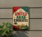 A vintage-style sign that reads "UNITED ARAB EMIRATES" with a cityscape and palm tree illustration, mounted on a wall.