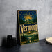 A vintage-style metal sign with the word "Vermont" prominently displayed, featuring a sunburst design and a mountain landscape.