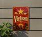 a vintage-style sign with the word "Vietnam" prominently displayed, along with a sun and clouds design, indicating a tropical or exotic location.
