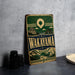 A vintage metal sign with the text "Wakayama" and an illustration of a Japanese temple, mountains, and a sunburst design, placed on a gray countertop next to some black camera lenses.
