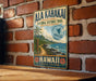 A vintage-style metal sign for the Ala Kahaki National Historic Trail in Hawaii, featuring a tropical beach scene with palm trees and a sailboat.