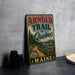 A vintage metal sign for the "Arnold Trail to Quebec" in Maine, featuring a scenic road and wilderness landscape.