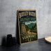A vintage metal sign for the Bayley Hazen Military Road in Vermont, featuring a scenic mountain landscape and a monument.