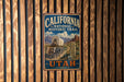 A vintage-style metal sign for the California-National Historic Trail, featuring an illustration of a person on a wagon and the text "California National Historic Trail" and "UTAH".