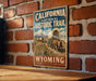 A vintage-style metal sign for the California National Historic Trail in Wyoming, featuring an illustration of a wagon train and mountains in the background.