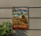 A vintage-style metal sign for the California National Historic Trail, featuring an illustration of a wagon train traveling through a desert landscape with mountains in the background.