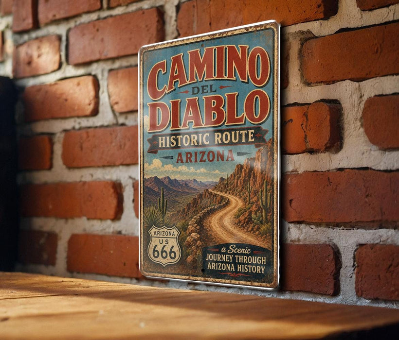 A vintage-style sign for the Camino del Diablo Historic Route in Arizona, featuring a scenic image of a winding road through the desert mountains.