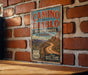A vintage-style sign for the Camino del Diablo Historic Route in Arizona, featuring a scenic image of a winding road through the desert mountains.