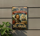 a metal sign with a portrait of a man, likely depicting John Smith, the first Englishman to live in the United States. The sign is mounted on a wall and is surrounded by greenery, including a plant.