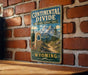 A vintage-style metal sign for the Continental Divide National Scenic Trail in Wyoming, featuring a mountain landscape and a trail marker.