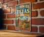 A vintage-style sign for the Camino Real trail in New Mexico, featuring a desert landscape with a cactus and a building in the background.