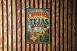 A vintage-style metal sign with the text "EL CAMINO REAL de los TEJAS TEXAS" hanging on a wooden wall.