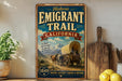 A vintage-style metal sign for the historic Emigrant Trail in California, featuring a wagon train and mountains in the background.