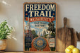 a vintage-style sign for the Freedom Trail in Massachusetts, with a statue of a man on a horse in the background. The sign is displayed on a shelf, surrounded by various kitchen items such as a cutting board, a lemon, and a potted plant.