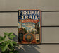 a vintage-style metal sign with the title "Freedom Trail" and the subtitle "Massachusetts Walk Through History", mounted on a wall.