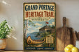A vintage-style metal sign for the Grand Portage Heritage Trail in Minnesota, featuring a canoe and a castle, is displayed on a shelf next to a wooden cutting board and some lemons.