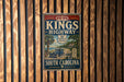 A vintage-style sign for Kings Highway, a South Carolina highway, mounted on a wooden wall.