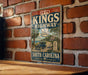 A vintage-style sign for Kings Highway in South Carolina, featuring a car and palm trees, mounted on a brick wall.