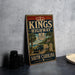 A vintage-style metal sign for Kings Highway in South Carolina, featuring a car and palm trees, is displayed on a countertop next to some black camera lenses.