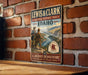 A vintage-style metal sign for the Lewis and Clark National Historic Trail in Idaho, featuring a scenic illustration of the trail and two figures in historical attire.