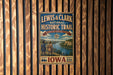 A vintage-style metal sign for the Lewis & Clark National Historic Trail, featuring a scenic illustration of a river and two figures in period clothing.