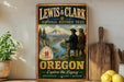 A vintage-style metal sign for the Lewis & Clark National Historic Trail in Oregon, featuring two figures in historical attire and a scenic landscape.