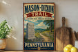 A vintage-style metal sign for the Mason-Dixon Trail in Pennsylvania, featuring a scenic illustration of a dirt path leading through a rural landscape with a monument and a wooden fence.