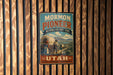 A vintage-style metal sign for the Mormon Pioneer National Historic Trail in Utah, featuring an illustration of a wagon and a couple of people.