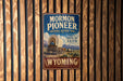 A vintage-style metal sign for the Mormon Pioneer National Historic Trail in Wyoming, featuring an illustration of a covered wagon and the text "Follow the path of faith".