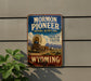 A vintage-style sign for the Mormon Pioneer National Historic Trail in Wyoming, featuring a wagon train and the text "Follow the path of faith" and "Wyoming".