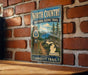 A vintage-style metal sign for the North Country National Scenic Trail, featuring a scenic illustration of a forest and a lake.
