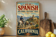 A vintage-style metal sign for the Old Spanish National Historic Trail in California, featuring a cowboy on horseback and a scenic landscape.