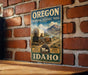 A vintage-style metal sign for the Oregon National Historic Trail, featuring an illustration of a covered wagon and mountains in the background.