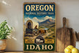 A vintage-style sign for the Oregon National Historic Trail, featuring a wagon pulled by a cow, with mountains and a river in the background.