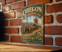 A vintage-style metal sign for the Oregon National Historic Trail, featuring an illustration of a covered wagon traveling through a scenic landscape.