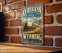 A vintage-style metal sign for the Oregon National Historic Trail, featuring an illustration of a covered wagon traveling through a scenic landscape with mountains in the background.