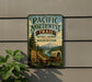 a vintage-style metal sign for the Pacific Northwest Trail Historic Corridor Washington, with a wagon train illustration and a mountain backdrop.