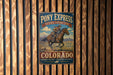 A vintage-style metal sign for Pony Express National Historic Trail in Colorado, featuring a cowboy riding a horse.