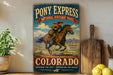 A vintage-style sign for Pony Express National Historic Trail in Colorado, featuring a cowboy riding a horse.