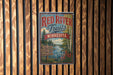 A vintage-style sign for the Red River Trail in Minnesota, featuring a scenic image of a river surrounded by trees and mountains.