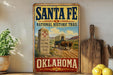 A vintage-style sign for Santa Fe National Historic Trail in Oklahoma, featuring a wagon and a desert landscape.