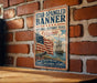 A vintage-style metal sign with an American flag and a sailing ship, mounted on a brick wall.