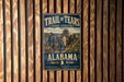 A vintage trail sign for the Trail of Tears, featuring a wagon train and people, mounted on a wooden wall.