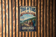 A vintage-style sign for the Trail of Tears, a National Historic Trail in Arkansas, featuring a scenic illustration of a group of people walking along a path through a forested area.